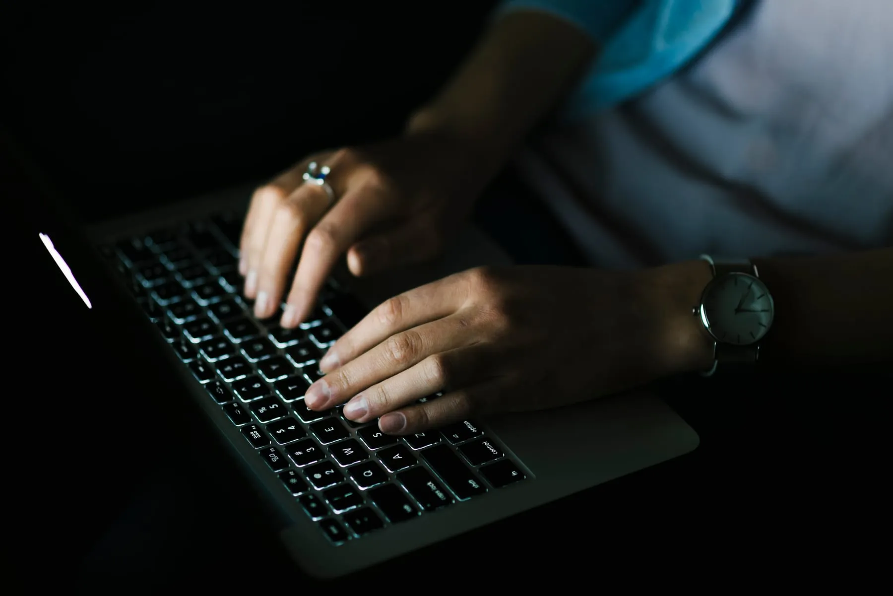 Crop woman using laptop dark room