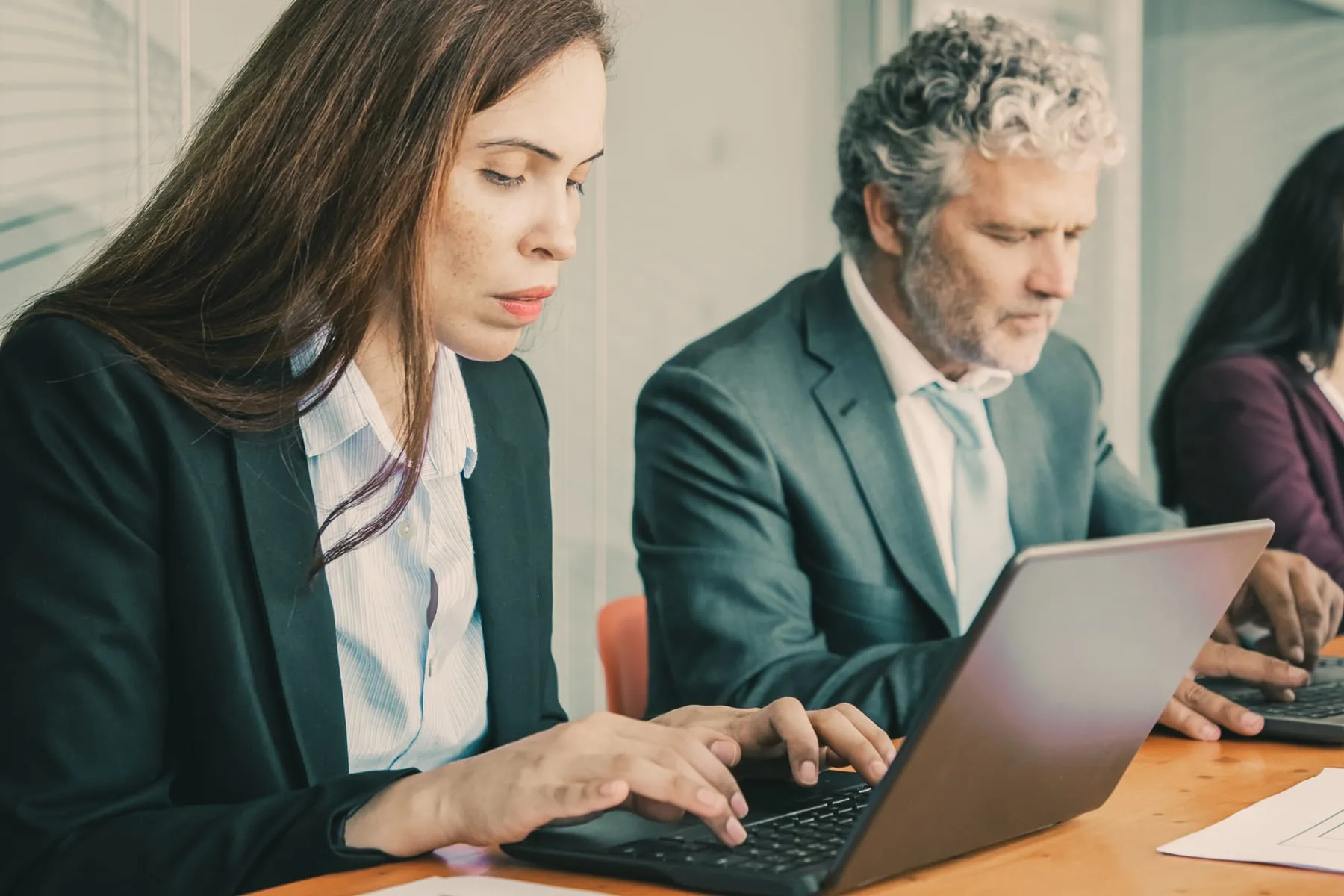 Row focused colleagues sitting one table using computers