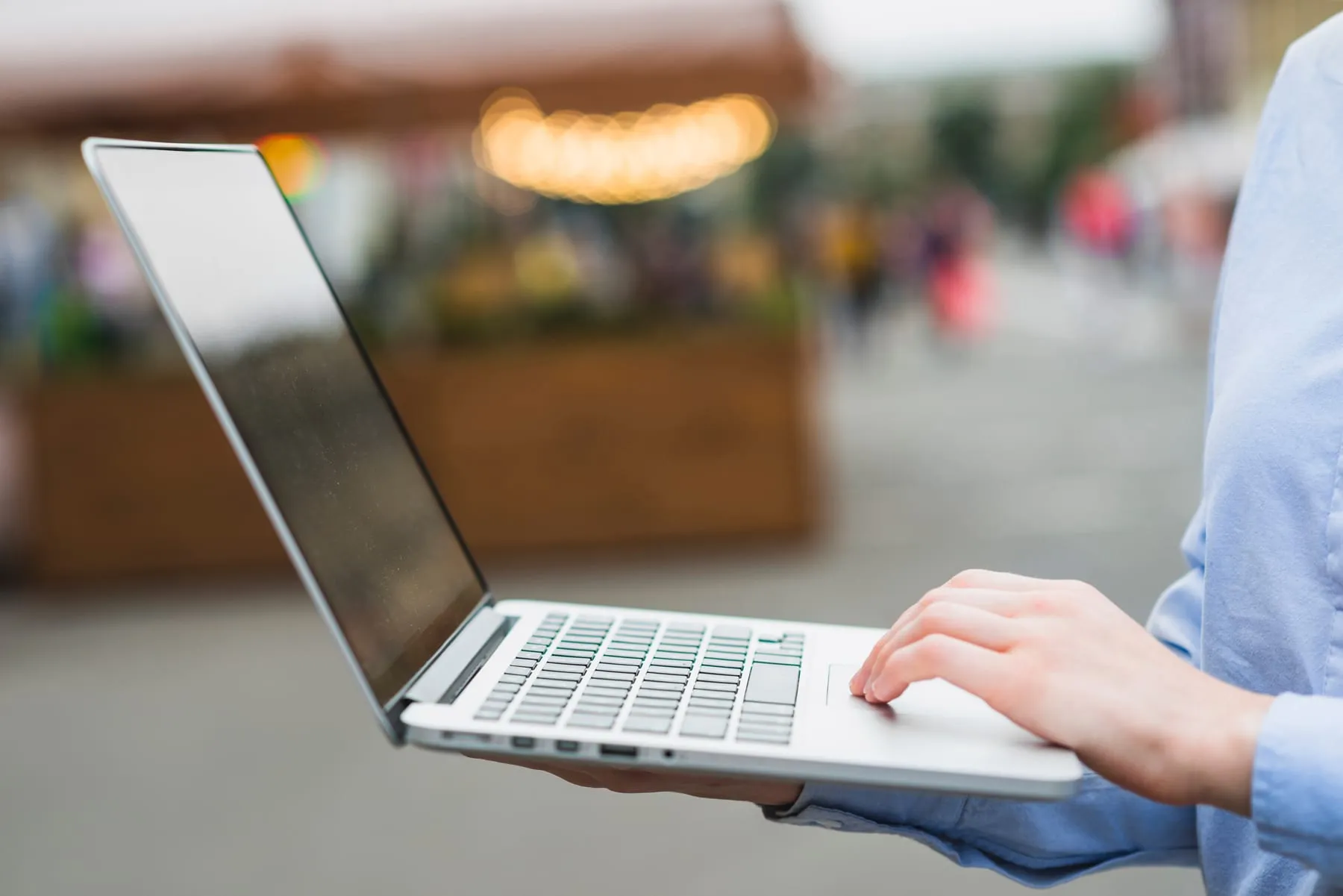 Human hand using laptop outdoors